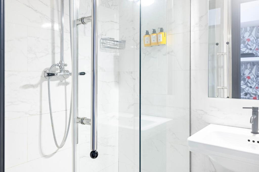 a white bathroom with a shower and a sink at Roma Luxus Hotel in Rome