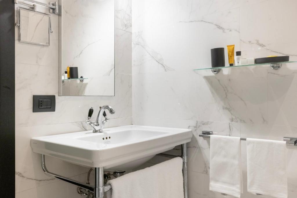 a white bathroom with a sink and a mirror at Roma Luxus Hotel in Rome