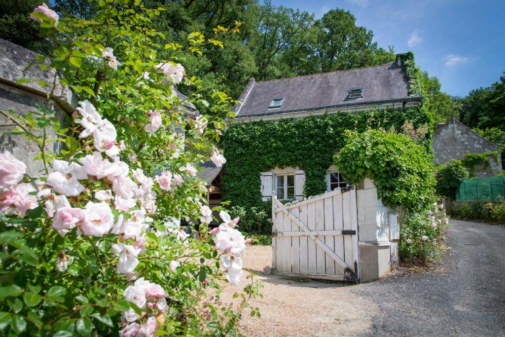a house with a gate and roses in front of it at Chambres d&#39;Hôtes Manoir de Montecler in Chènehutte-les-Tuffeaux