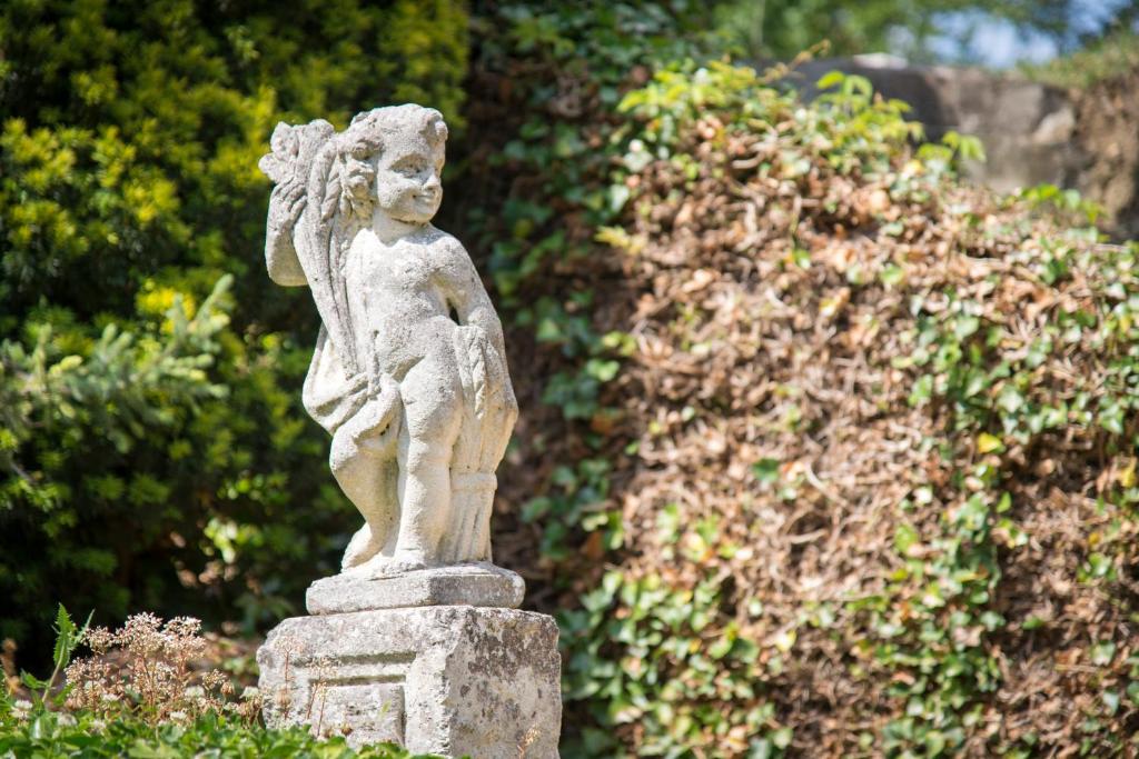 a statue of an angel standing in a garden at Chambres d&#39;Hôtes Manoir de Montecler in Chènehutte-les-Tuffeaux