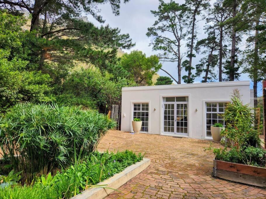 een wit gebouw met bomen op de achtergrond bij Mountain Vineyard Cottage in Kaapstad