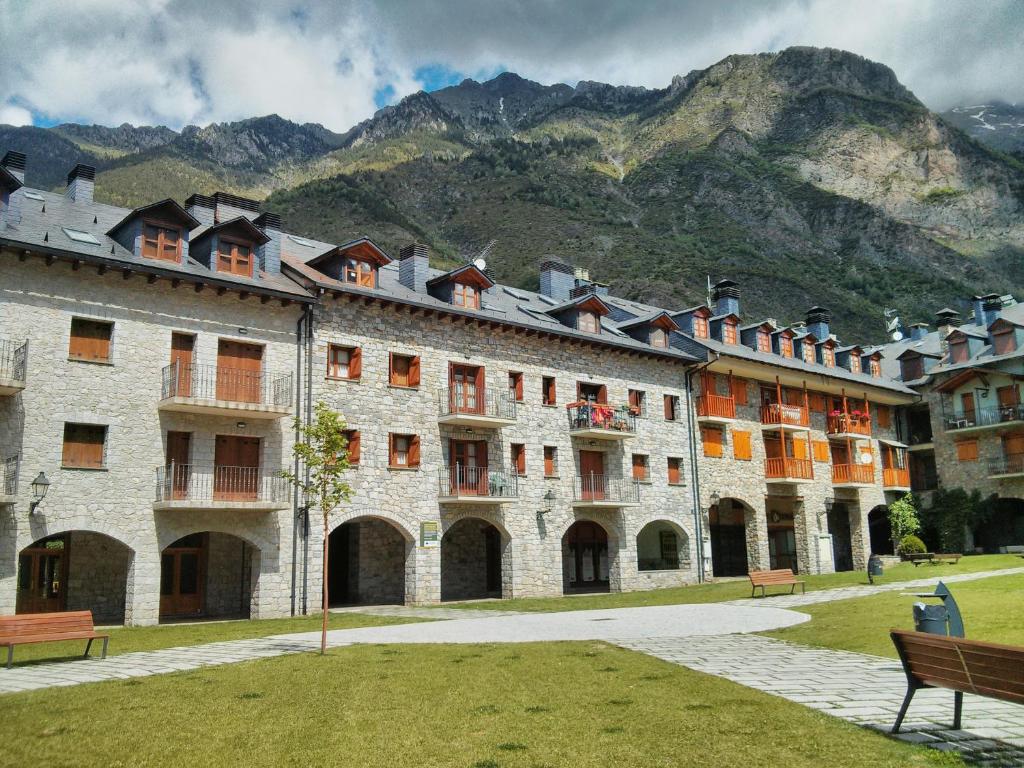 un gran edificio de piedra con una montaña en el fondo en Apartamento Lamatriz Dequin Edificio Sayo 8, en Benasque