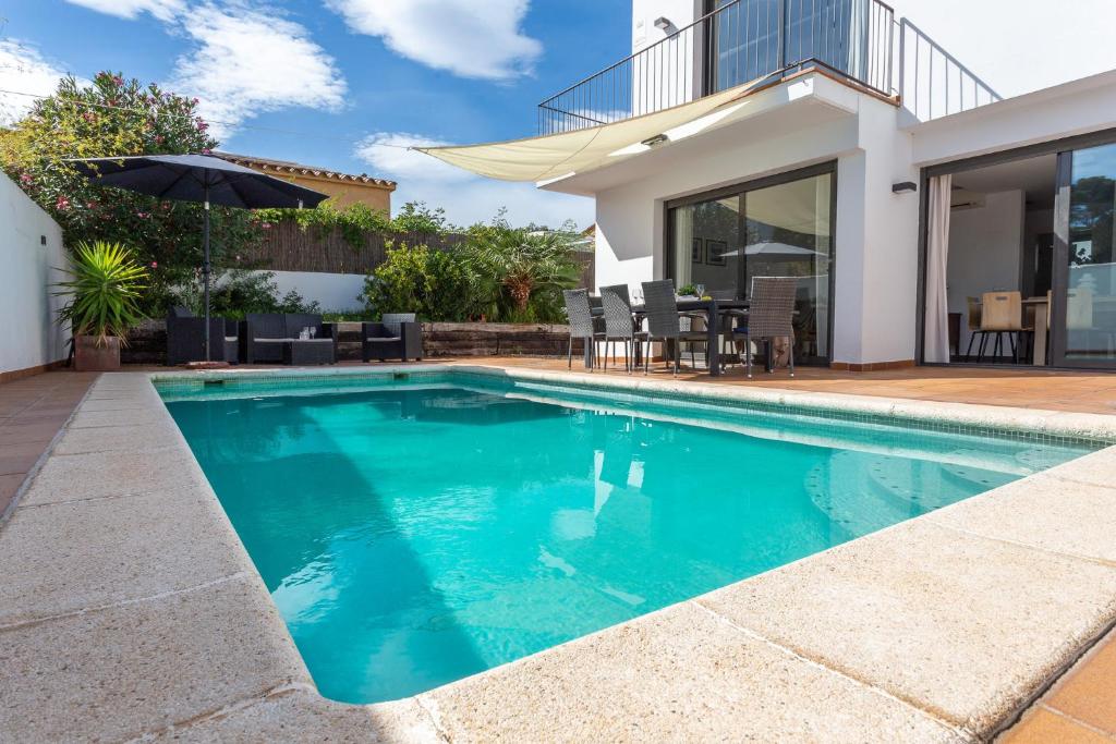 a swimming pool in front of a house at Casa Alexandra in L'Escala