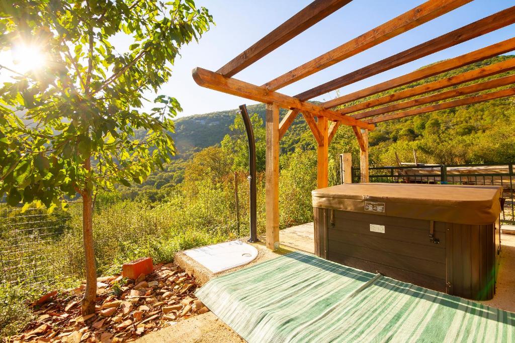 a hot tub under a pergola with a view of the mountains at Woodland Retreat in Donji Zagon
