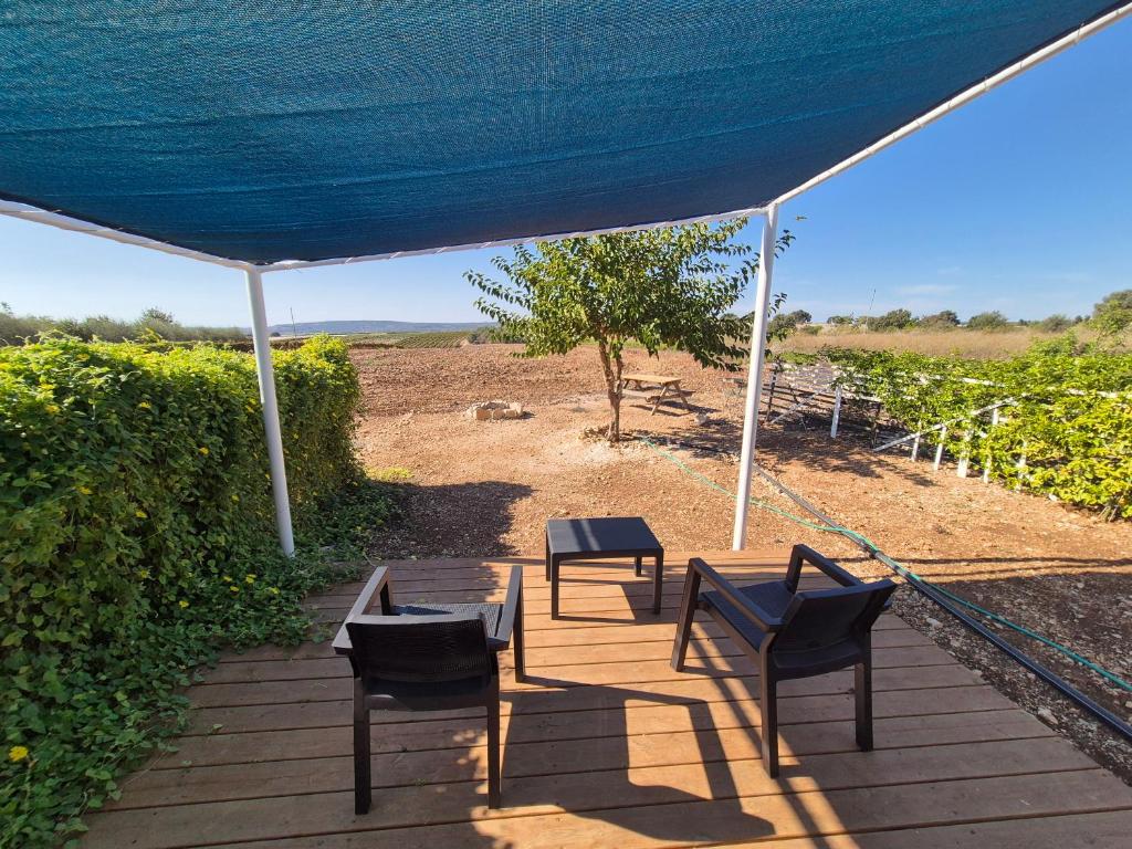 a patio with two chairs and a table under a blue tent at Adas in Aviʼel
