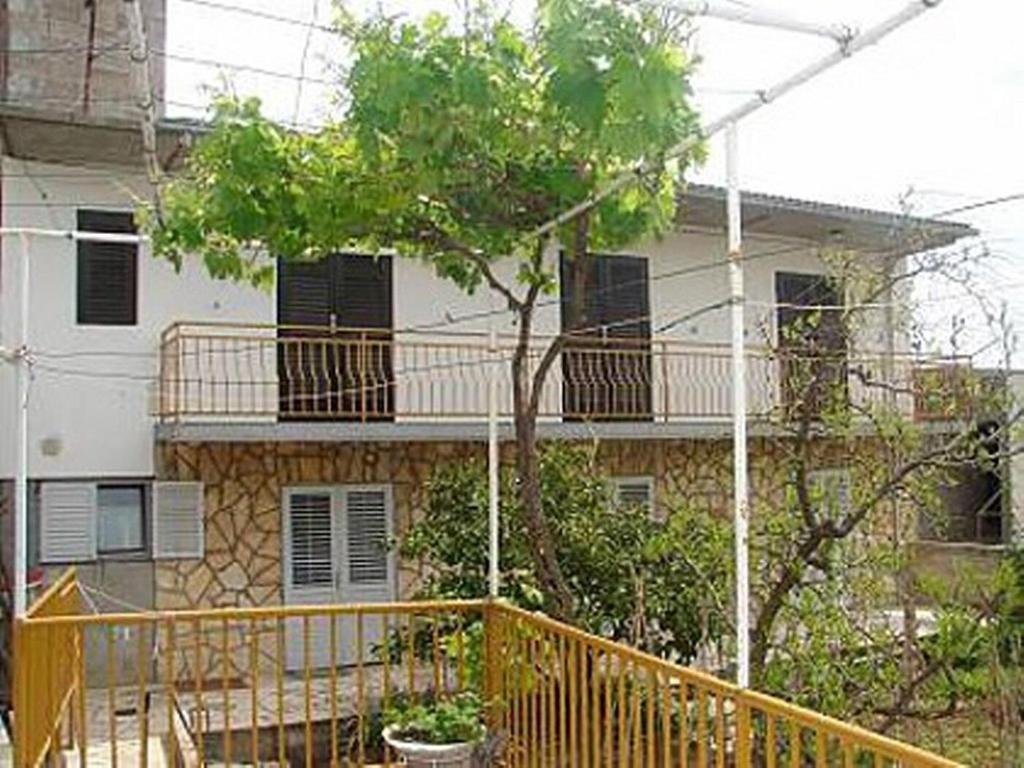 ein Gebäude mit einem Balkon und einem Baum davor in der Unterkunft Apartment Marin in Tisno