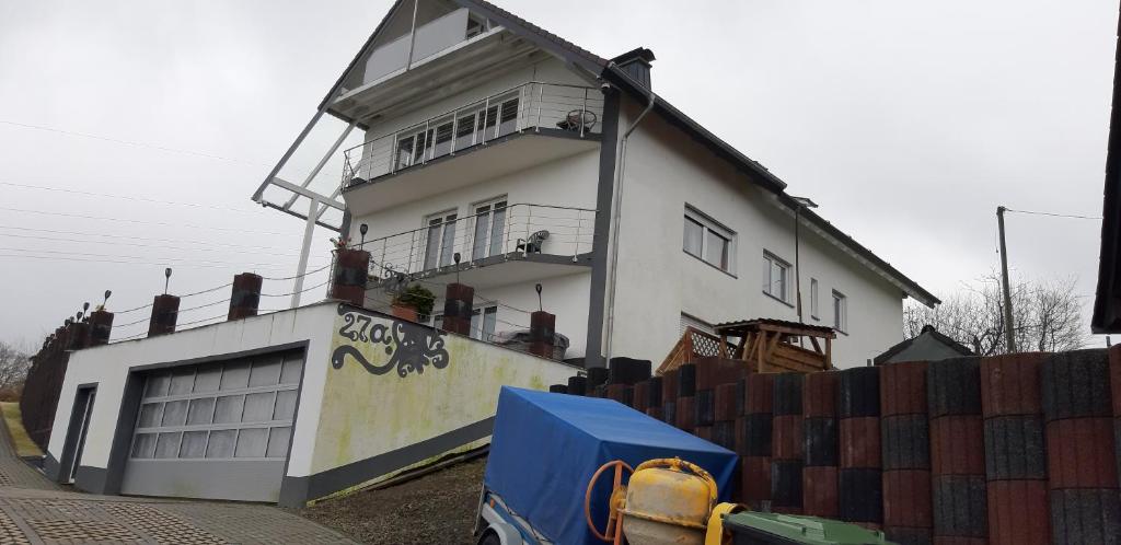 ein weißes Haus mit einem Zaun davor in der Unterkunft Ferienwohnungen mit Weitblick in Bergneustadt