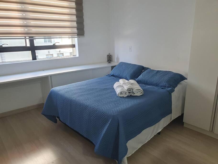 una camera da letto con un letto blu con due asciugamani sopra di Flat com Ar, SmarTV43, wifi, estac, novo, Selenita2 a Barueri