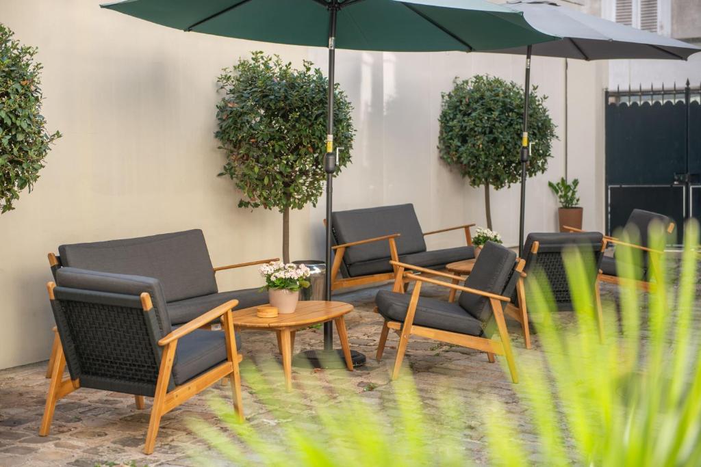 a group of chairs and a table with an umbrella at Hôtel Helzear Montparnasse by Esteem in Paris