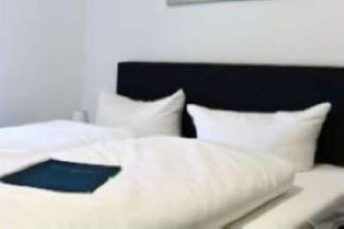 a white bed with white pillows and a black headboard at Hotel Restaurant Harrier Hof in Brake