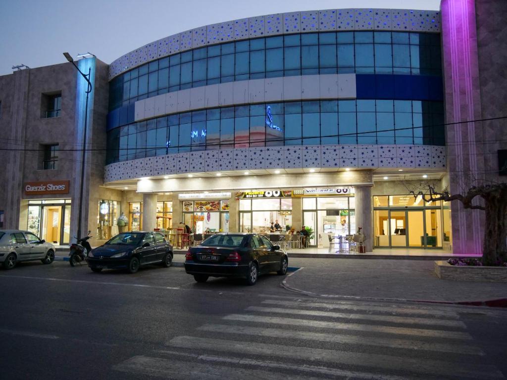 米多恩Hotel Djerba Inn的前面停着汽车的建筑物