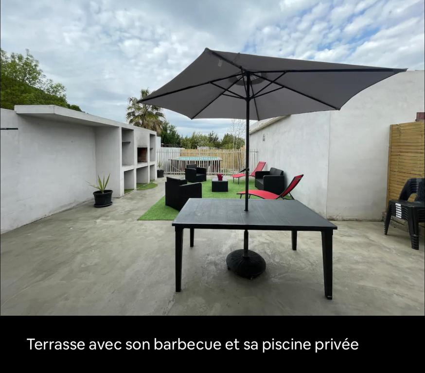 a table with an umbrella on a patio at Villa agréable in Villedaigne