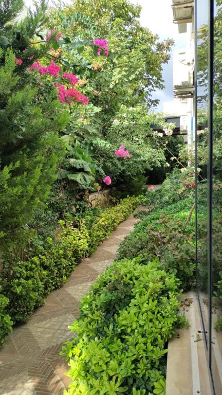 a path through a garden with pink flowers at Port Hotel, Tasucu in Silifke
