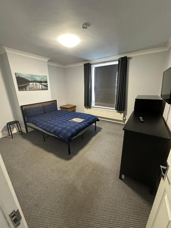Una habitación con una cama y un escritorio y una ventana. en Large 5 bedroom property in the centre with lots of parking, en Boston