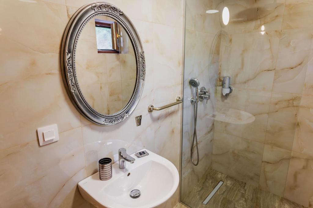 a bathroom with a sink and a shower with a mirror at Roua Dimineții in Rucăr