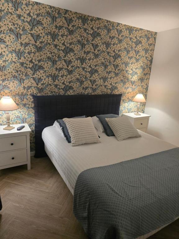 a bedroom with a bed and two night stands with lamps at Hôtel L'ideal le Mountbatten in Arromanches-les-Bains