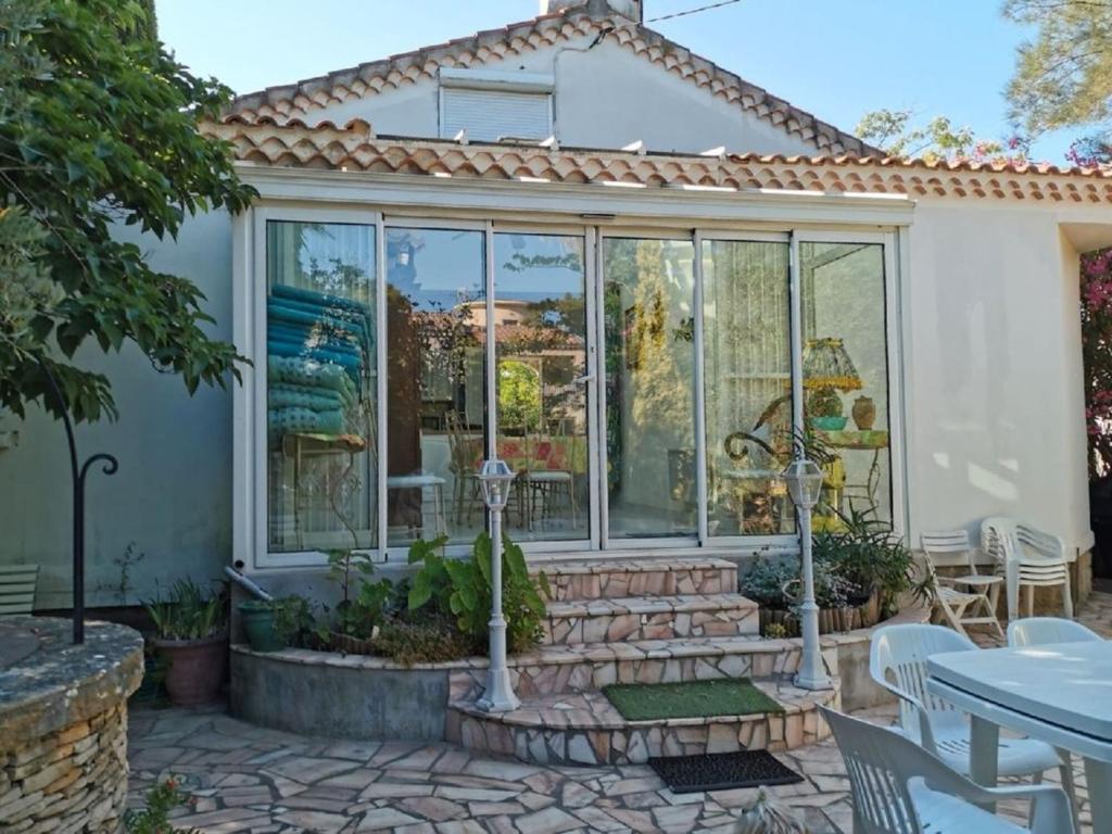 une véranda avec des portes en verre sur une terrasse dans l'établissement Villa 7 pers plage à 100m, à Saint-Cyr-sur-Mer
