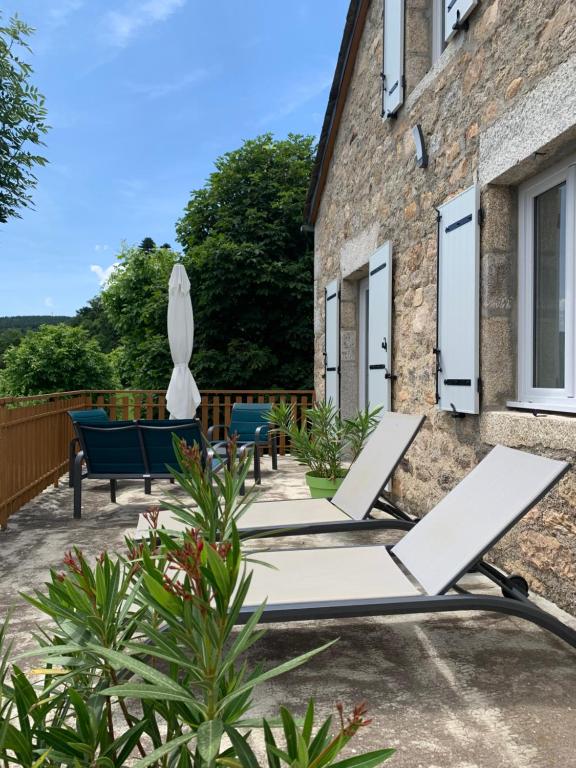 un patio con due sedie a sdraio e un ombrellone di Chez Marie ad Albaret-Sainte-Marie