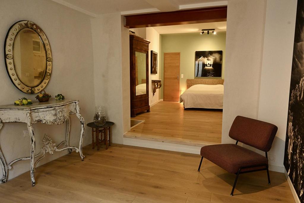 Cette chambre comprend un lit, un miroir et une chaise. dans l'établissement Suite dans maison d'artiste, à LʼIsle-sur-la-Sorgue