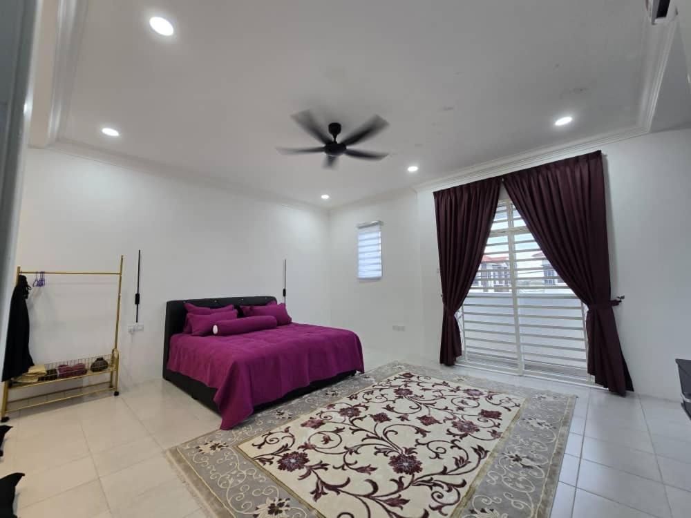 una camera con letto viola e ventilatore a soffitto di The Bangau Cottage a Sungai Petani