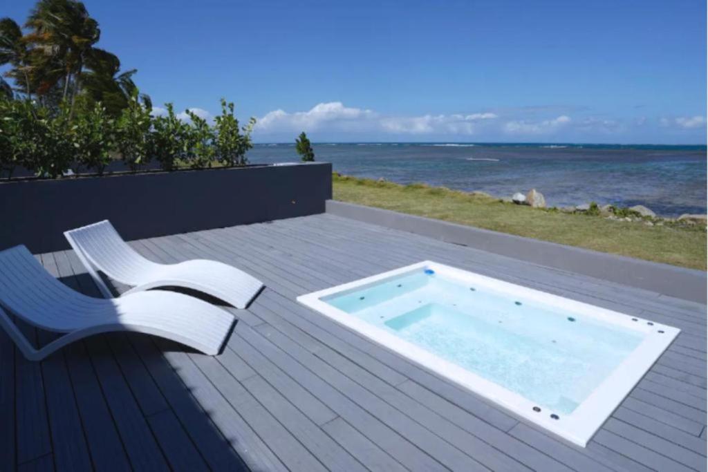 Trujillo AltoにあるVilla Familiar frente al mar Puerto Ricoのホットタブ(椅子付きのデッキに座る)