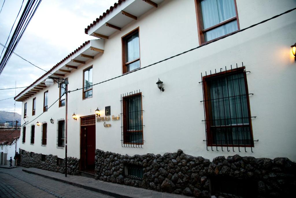 un edificio bianco con finestre e porta rossa di Taypikala Hotel Cusco a Cuzco