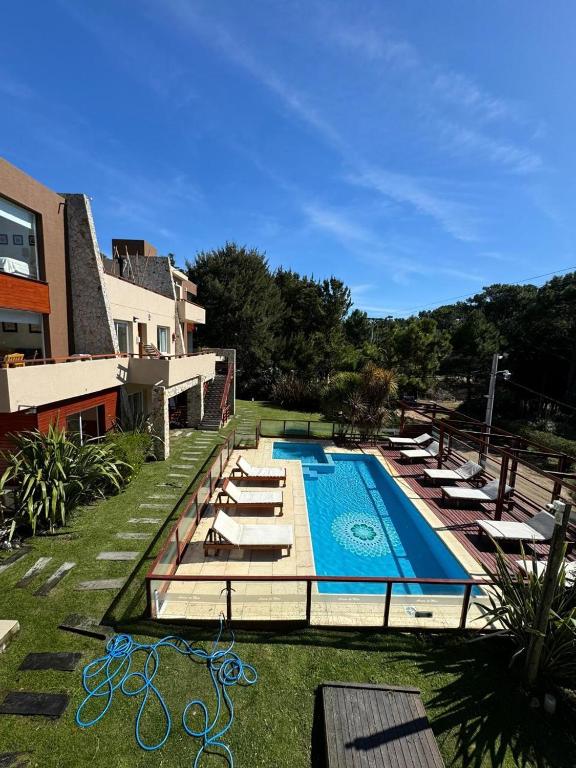 a swimming pool with loungers and chairs next to a building at Arena de Mar Depto E in Mar de las Pampas