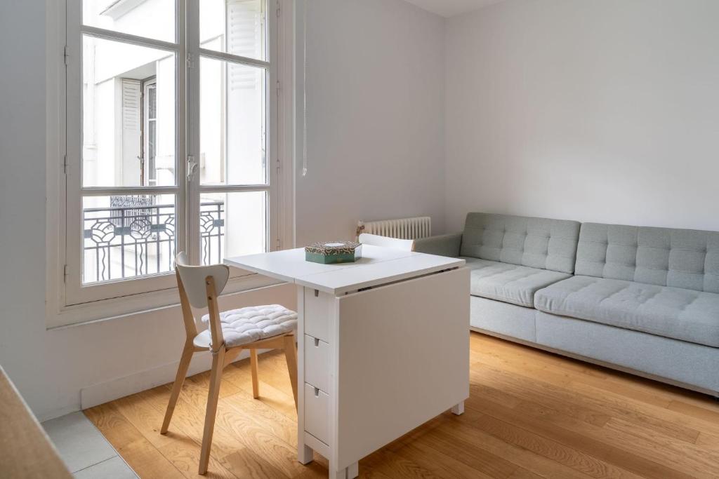 un salon avec une table blanche et un canapé dans l'établissement Airy and Stylish 1BD Flat ile Saint-Louis, à Paris