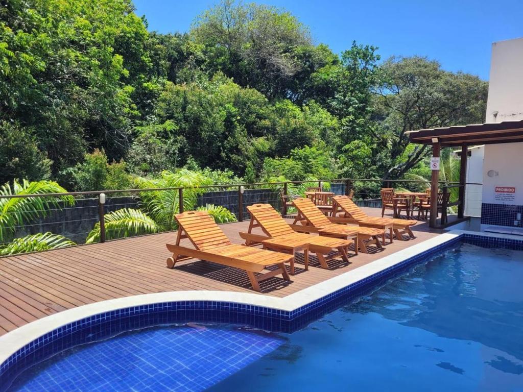 a group of chairs sitting on a deck next to a swimming pool at Flat Maré 3 - 2da praia condomínio com piscina, Morro de Sao Paulo in Morro de São Paulo