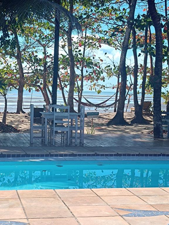 a picnic table and bench next to a swimming pool at Pousada ZEN Cumuruxatiba in Cumuruxatiba