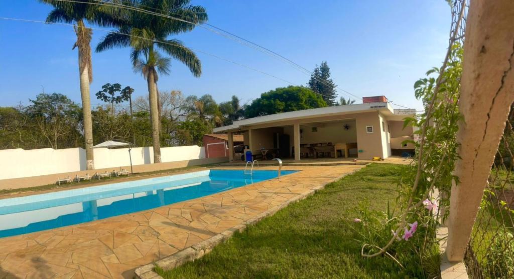 a house with a swimming pool in front of it at Chácara Boa Vista Santa Isabel SP in Santa Isabel