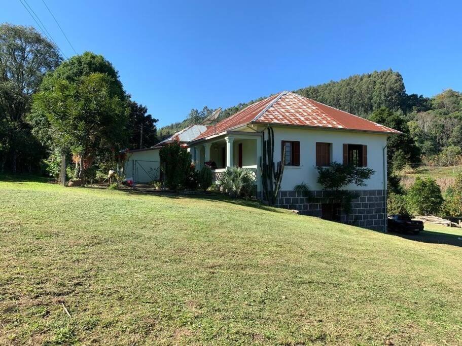 a small white house with a grass yard at Colonia Nona Angélica in Farroupilha