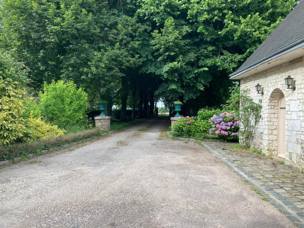a dirt road with trees and a house and flowers at La maison des fleurs in Saint-Arnoult