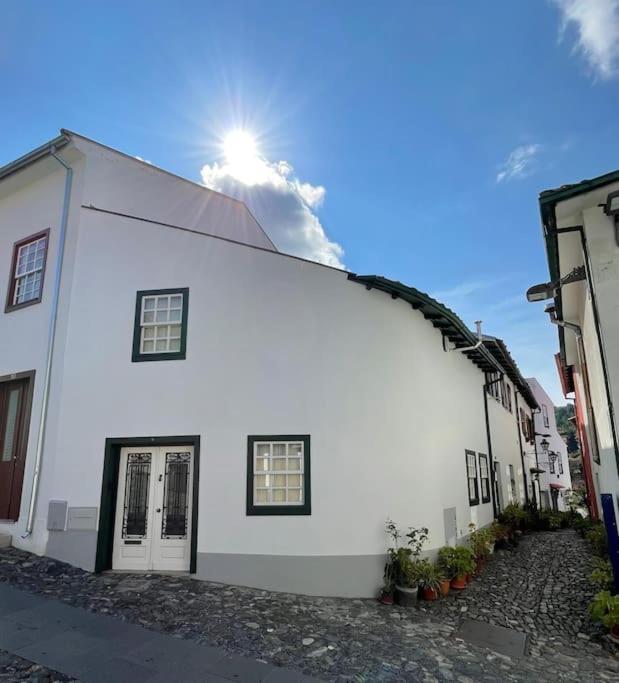 a white building with the sun behind it at Casa do Arco da Velha in Bragança