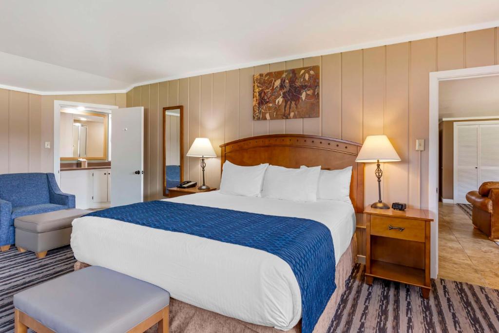 a hotel room with a large bed and a chair at Best Western Sunset Inn in Cody