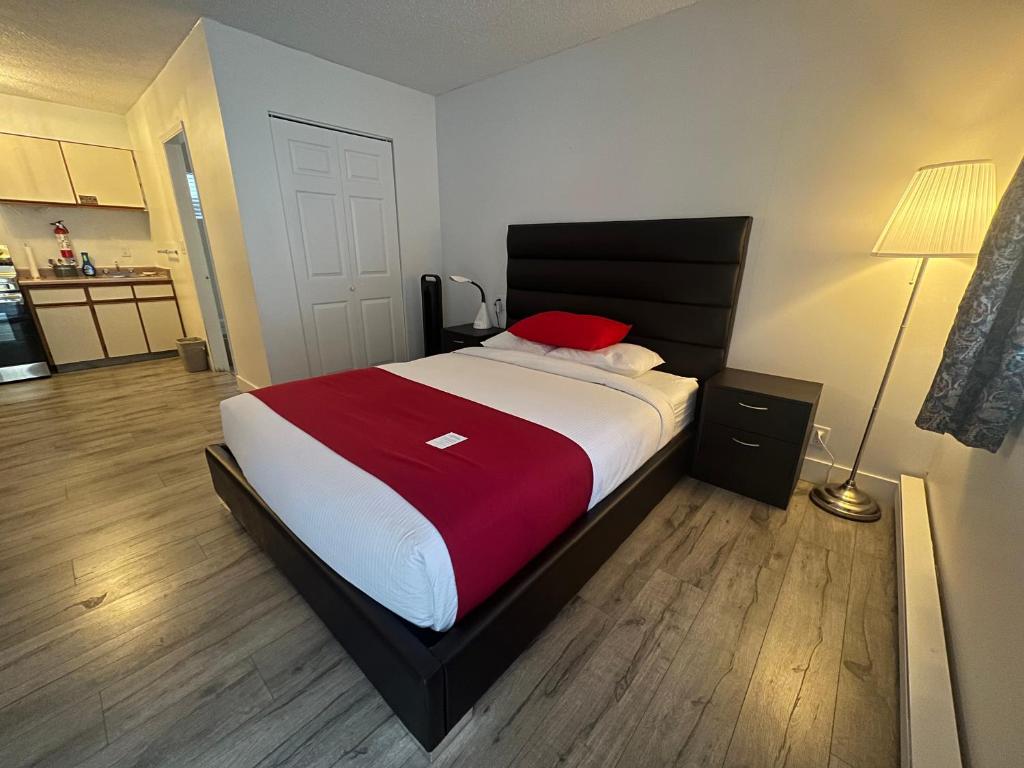 a bedroom with a large bed with a red pillow at Alpine Motel in Hope