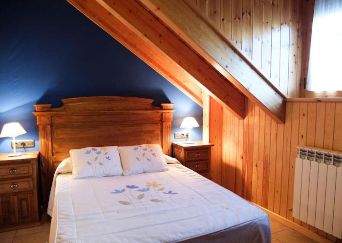 1 dormitorio con cama y pared azul en Apartamentos Fogaron, en Saravillo