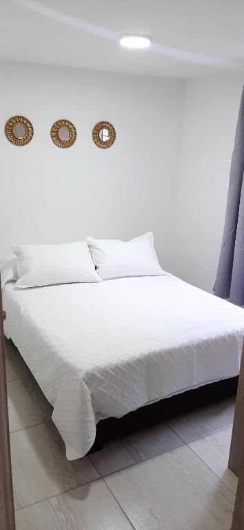a bedroom with a white bed with white sheets at Apartamento comodo a 15 minutos del Aeropuerto JMC in Rionegro
