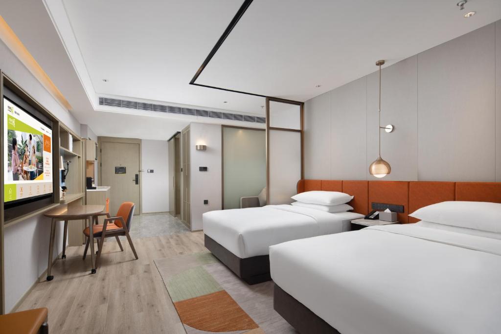 无锡Home2 Suites By Hilton Wuxi Huishan的一间酒店客房,设有两张床和电视