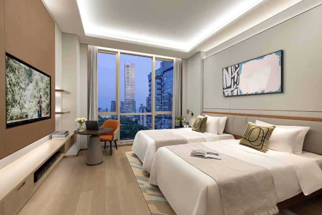 a hotel room with two beds and a large window at Somerset QPlex Shenzhen in Shenzhen