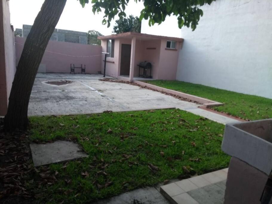 Un patio con un árbol y un edificio rosa. en CasaMadero, en Ciudad Madero