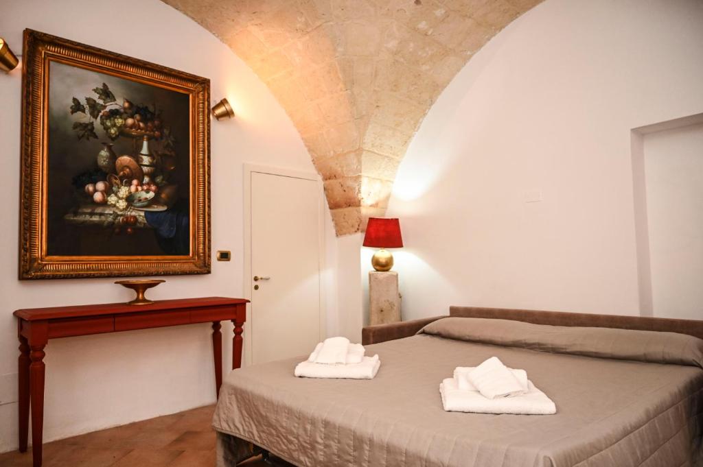 Un dormitorio con una cama y un cuadro en la pared. en Il Voltone - Vivi Salento, en Copertino