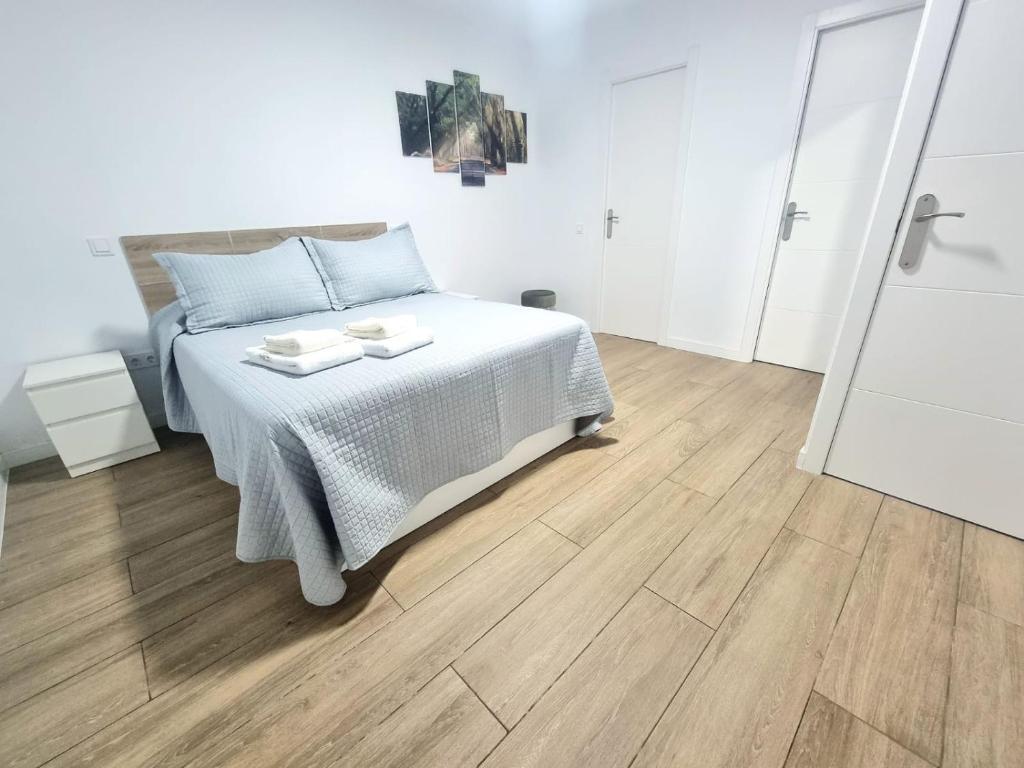 a white bedroom with a bed and a wooden floor at Vivienda El Viajero in Valverde