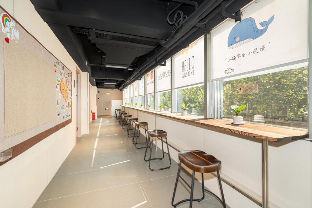 a row of stools in a classroom with a row of windows at 际庭青年旅舍-马当路地铁站店 in Shanghai