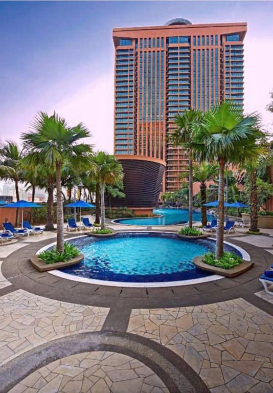 クアラルンプールにあるBintang Sky Villa Suites Times Square KLのヤシの木と高い建物のあるリゾートプール