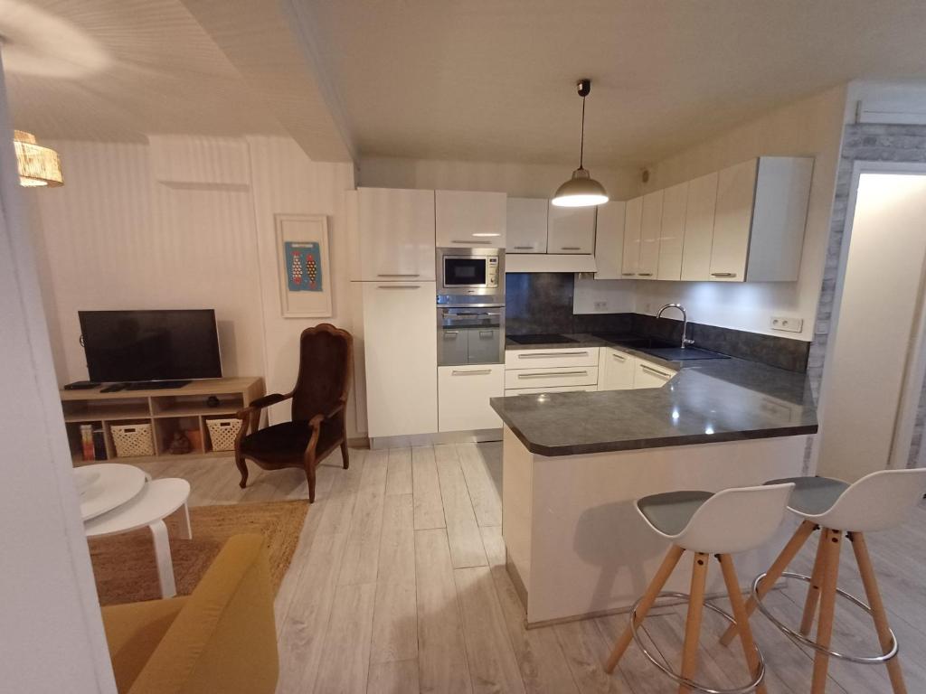 une cuisine avec des armoires blanches et une table et des chaises dans l'établissement Apt-rénové-chic-Préfecture-Cœur de Marseille, à Marseille