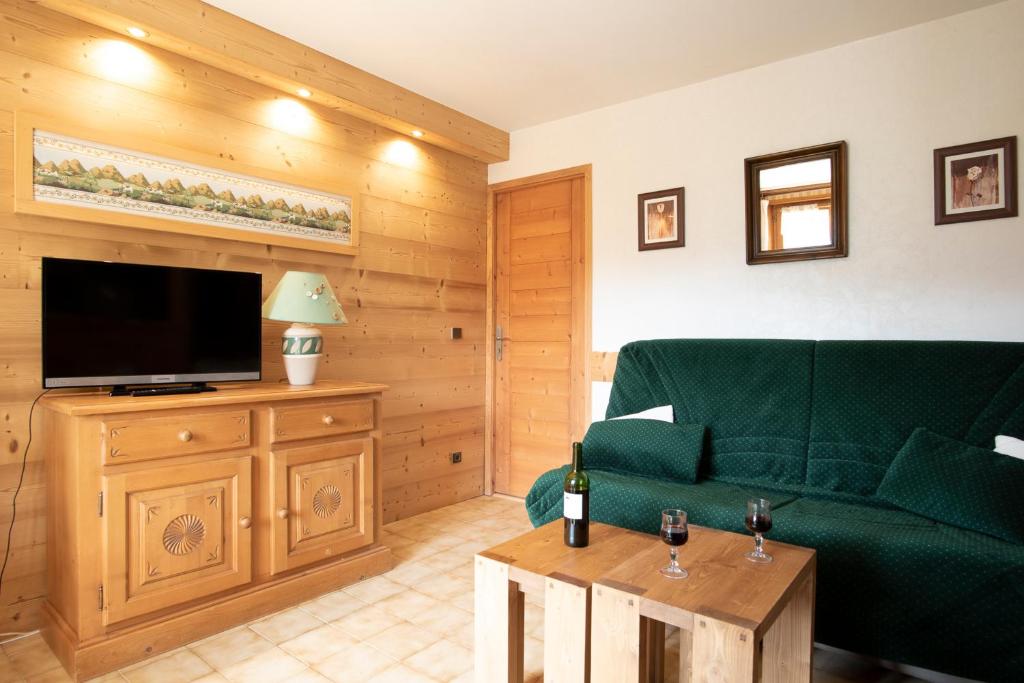 un salon avec un canapé vert et une télévision à écran plat dans l'établissement Chalet Rochebrune - Apartment La Turche, aux Gets