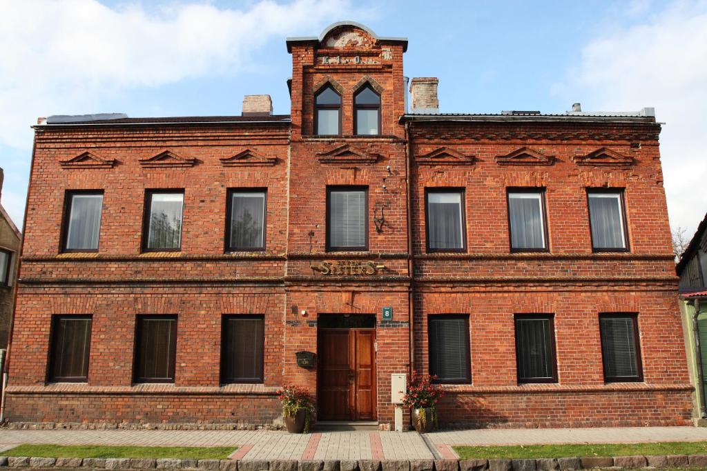 an old red brick building with a clock tower at Seven Sisters Apartments with Self Check-In in Liepāja