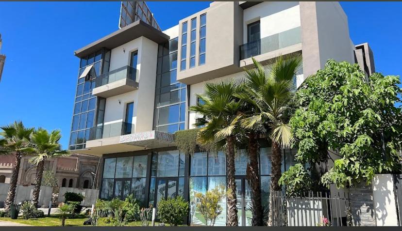 Un edificio con palmeras delante. en Les crêtes dar bouazza, en Casablanca