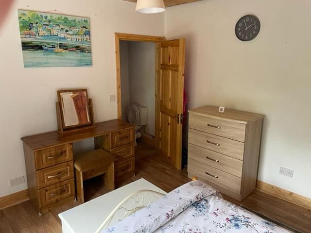 卡舍尔The Cottage Greenacre House, Carrow, Dualla, Cashel, County Tipperary E25T672的一间卧室配有一张床、梳妆台和时钟